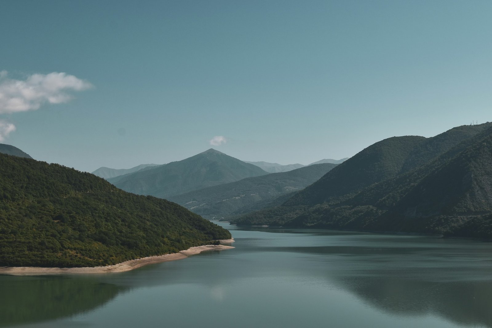 A calm drinking water reservoir between forested mountains