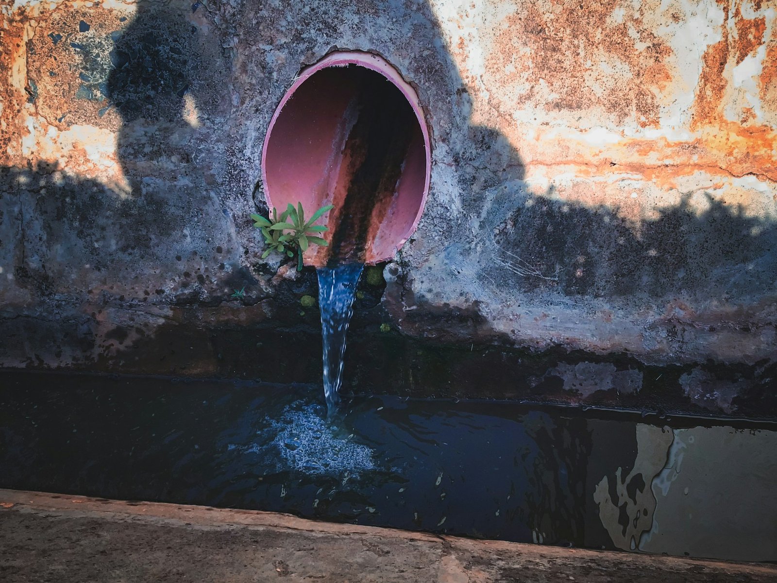 An industrial outfall pipe discharging effluent into a settling pond
