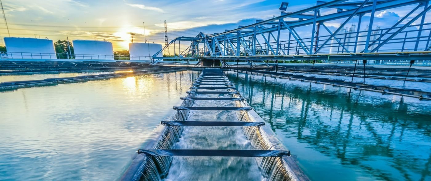 Sedimentation basins at a water treatment plant, with treated water flowing over weir plates at sunrise
