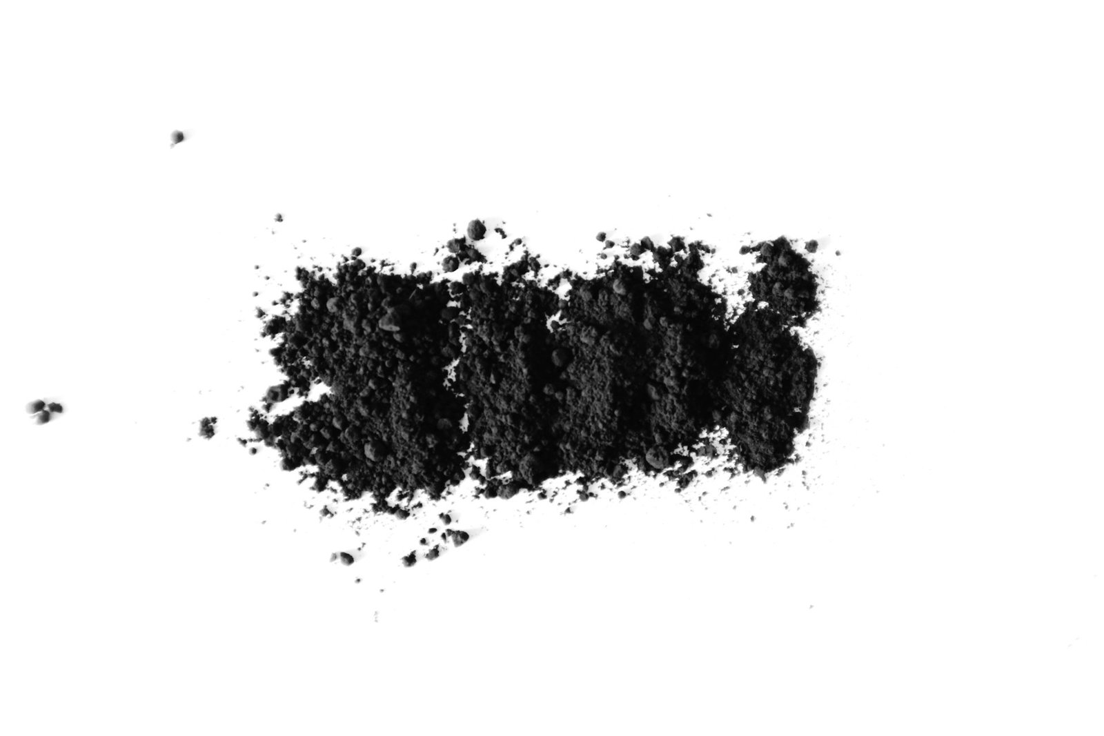 Fine black activated carbon powder spread on a white surface